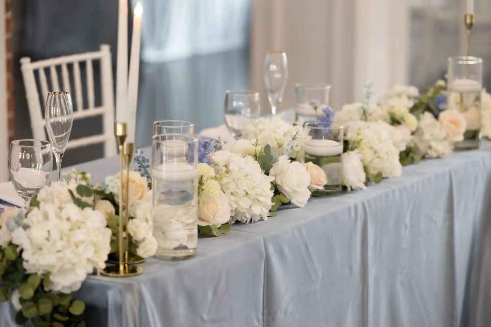 Head table styled with elegant silk florals from Sherpa’s luxury wedding floral rentals in DFW, featuring soft white arrangements and greenery for a timeless reception look.